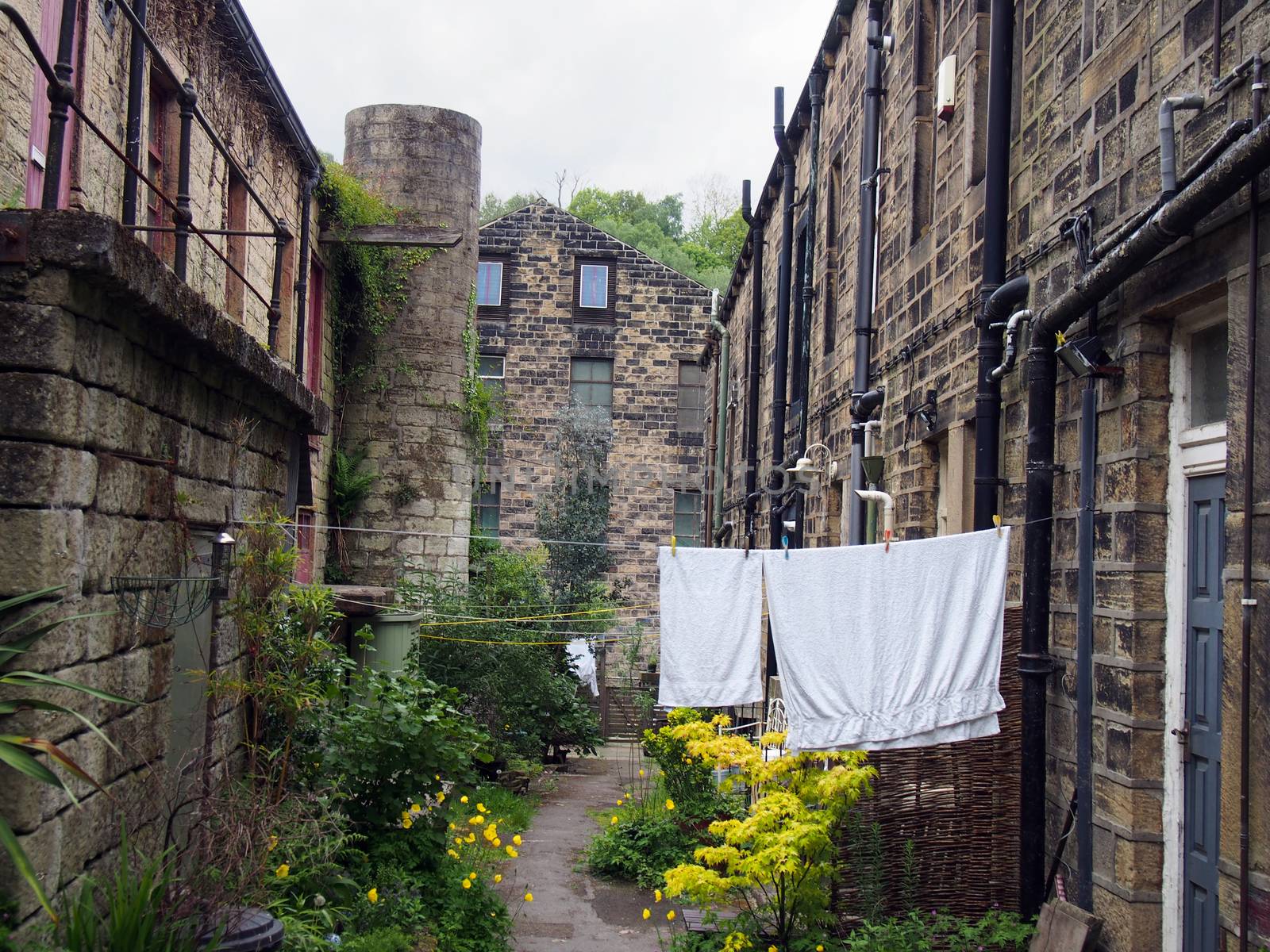 a row of typical traditional yorkshire stone houses in a small terraced street with garden flowers and washing drying on a line in hebden bridge