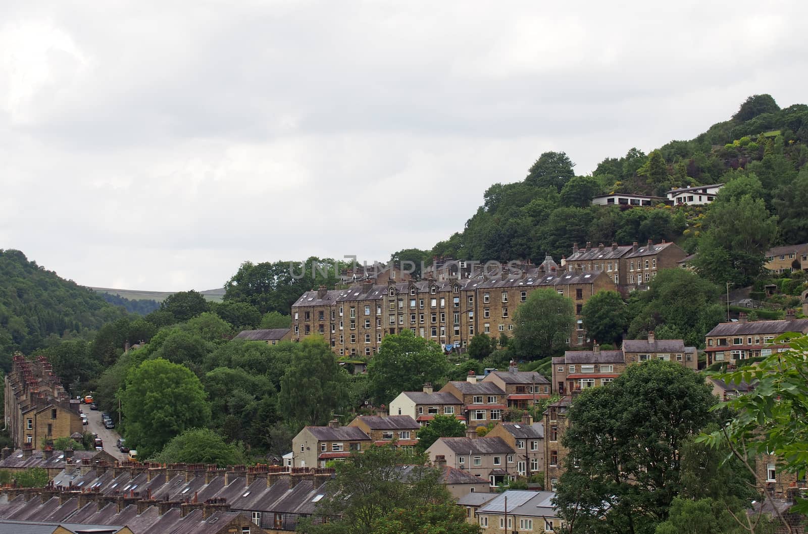 a view of the streets and houses of hebden bridge between trees and calder valley landscape in west yorkshire