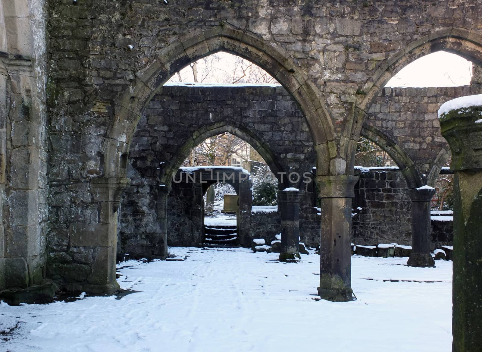 arches and columns in the ruined medieval church in hebden bridge west yorkshire with snow covering the ground in winter