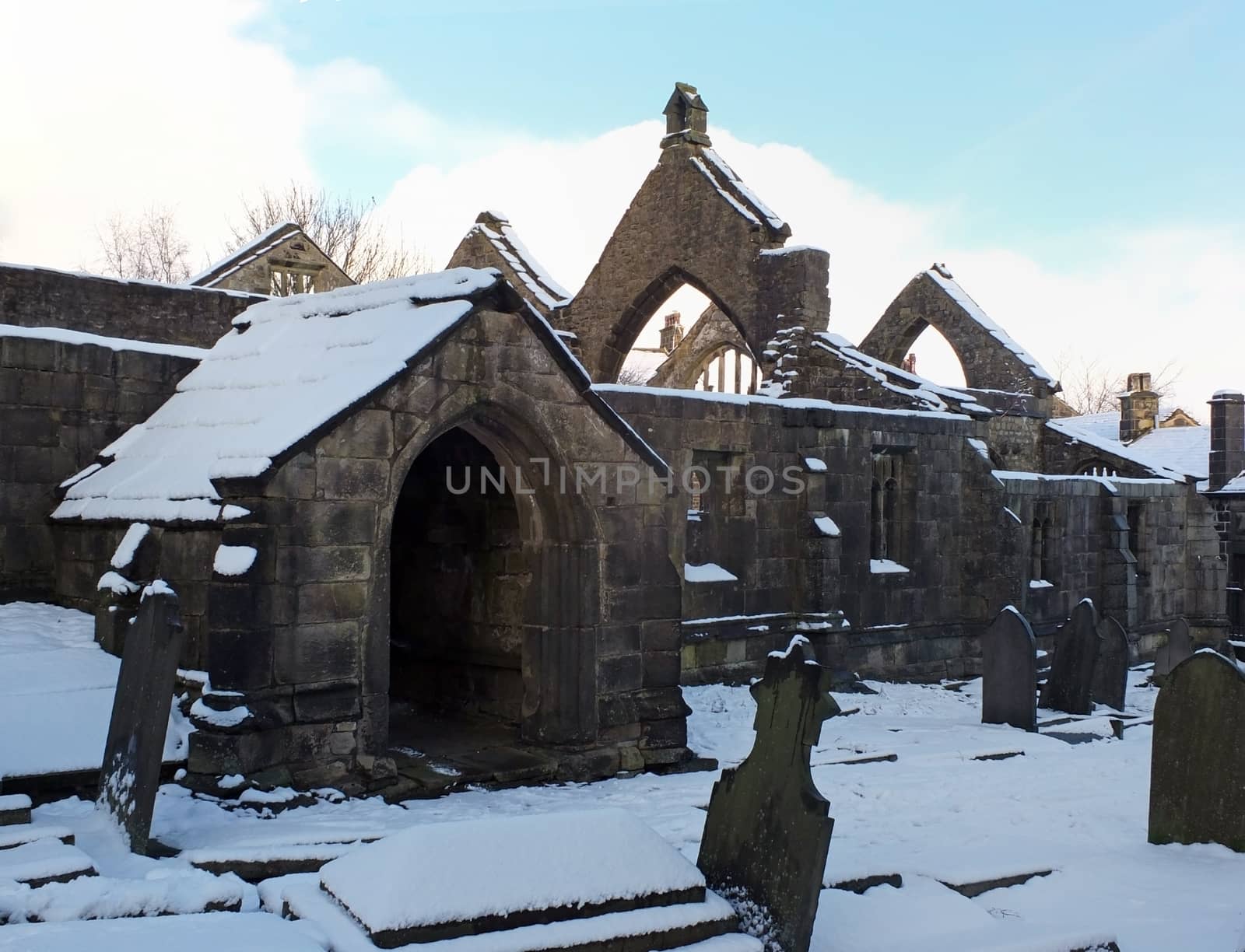 ruined medieval church in heptonstall in west yorkshire covered in snow in winter with a blue sky