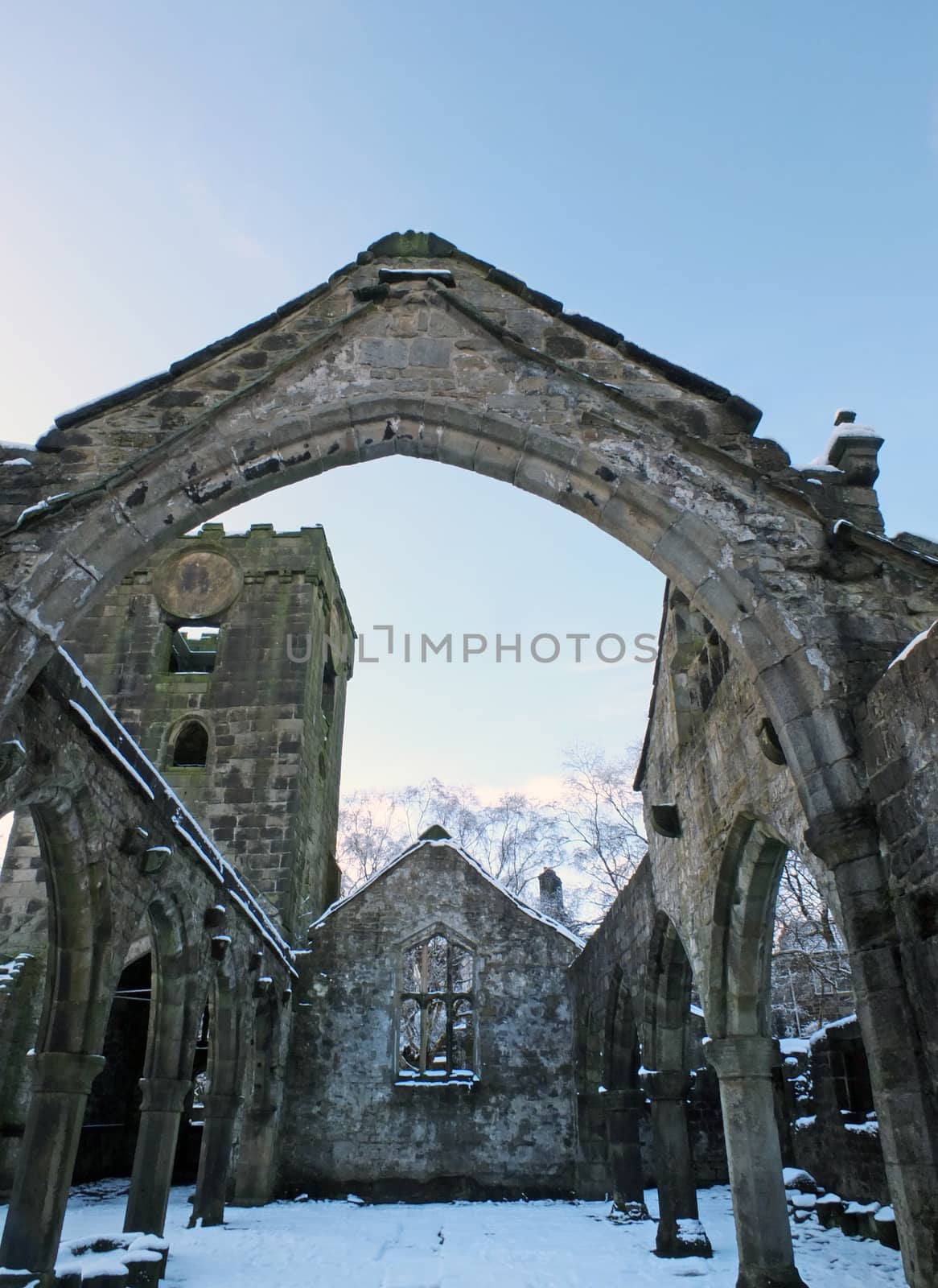 the medieval ruined church in heptonstall covered in snow showing arches and columns against a blue winter sky