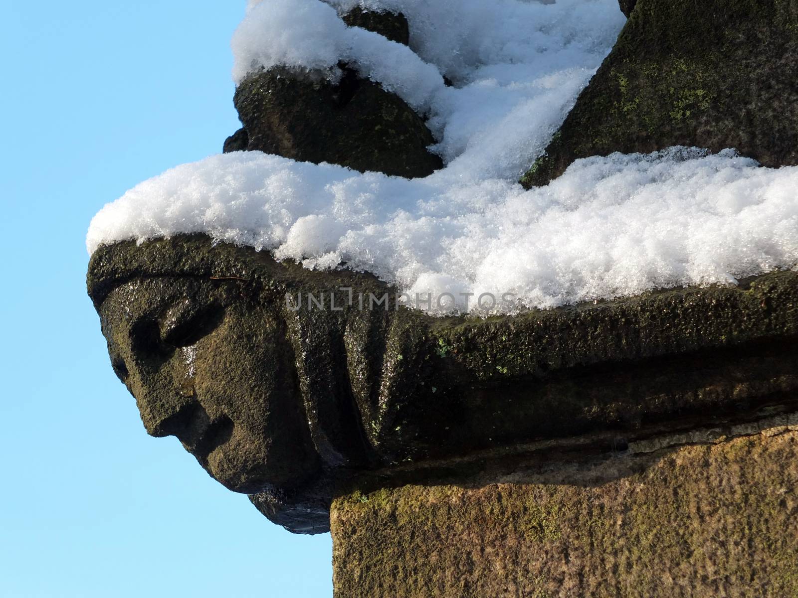 close up of the carving of a womans face in profile on the corner of the ancient ruined medieval church in heptonstall west yorkshire covered in winter snow