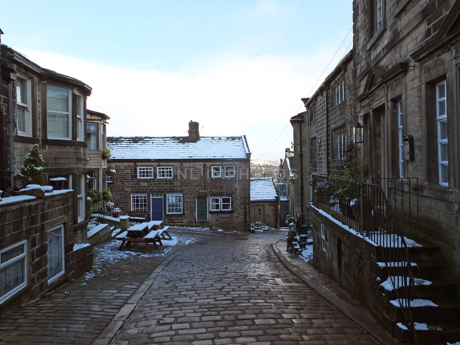 the historic yorkshire village of heptonstall in winter with snow covered roofs and street by philopenshaw