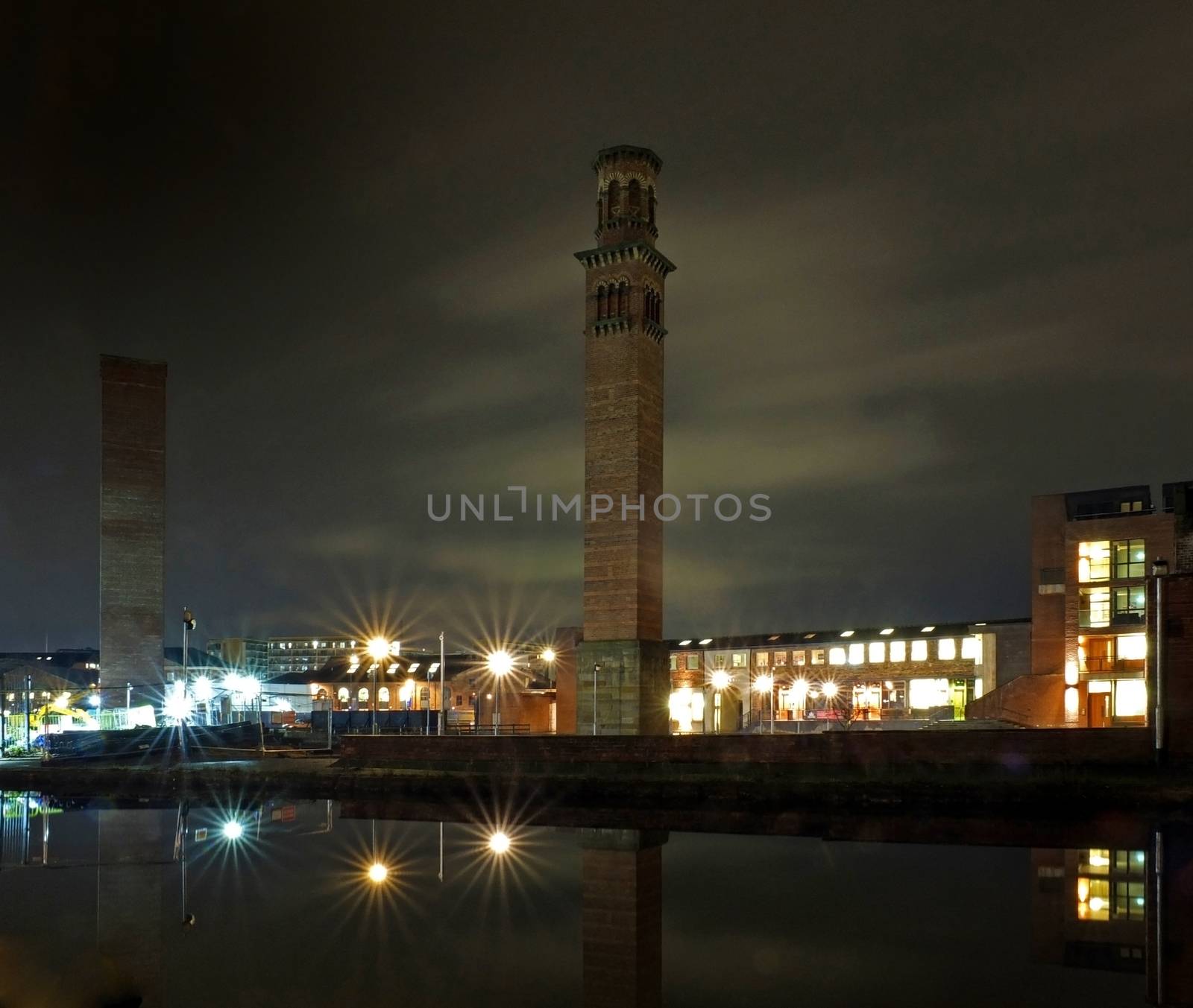 cityscape view of holbeck in south leeds showing the historic tower works at night with office building and lights reflected in the canal by philopenshaw