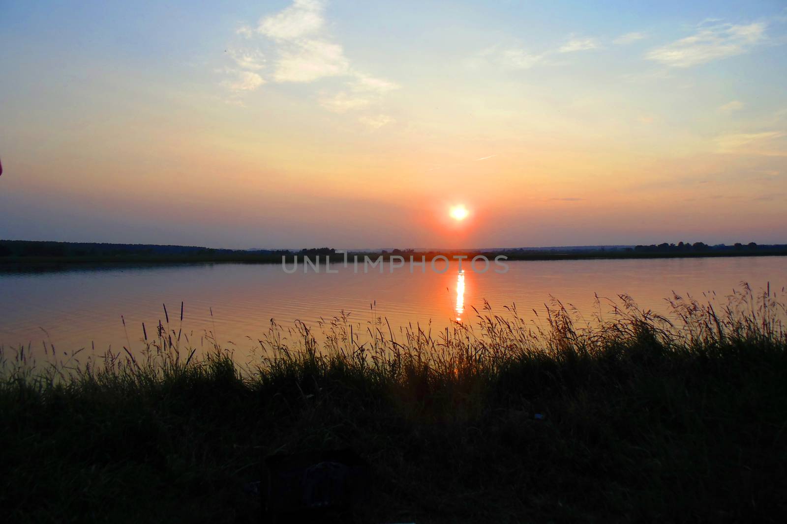 beautiful sunset over the lake and forest. by Annado