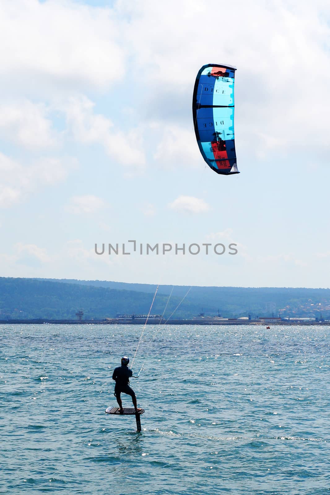 a man is kiting the sea on a sunny windy day. by Annado