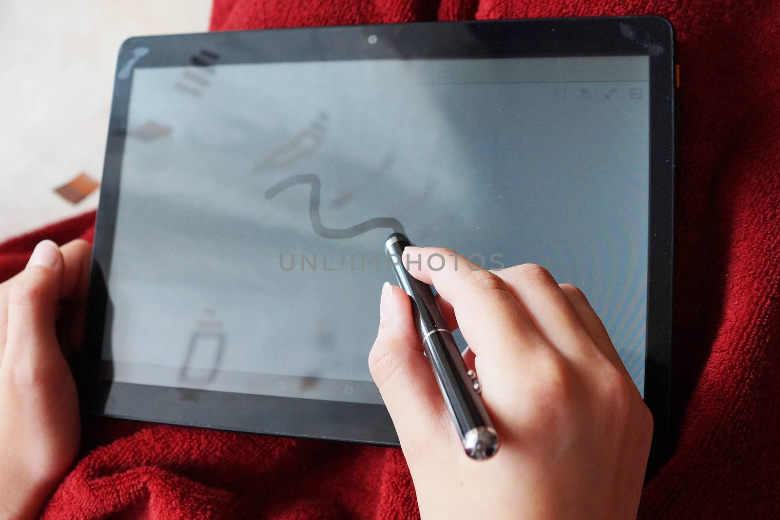 hand writes with a stylus on the white screen of the tablet by Annado