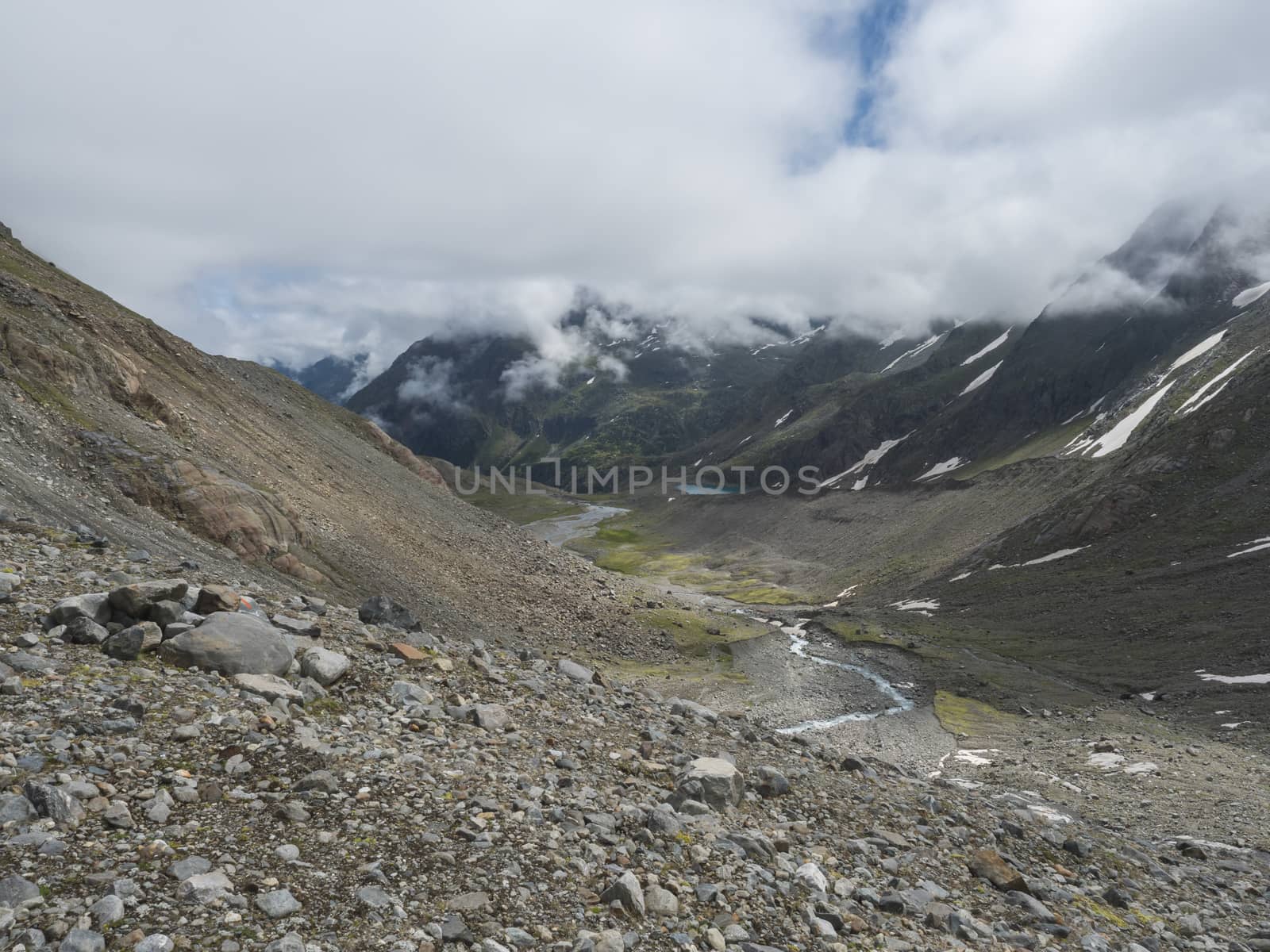 Summer view of alpine mountain valley with winding stream and glacial lake, Sulzenauferner Glacier, Stubai Alps, Austria.