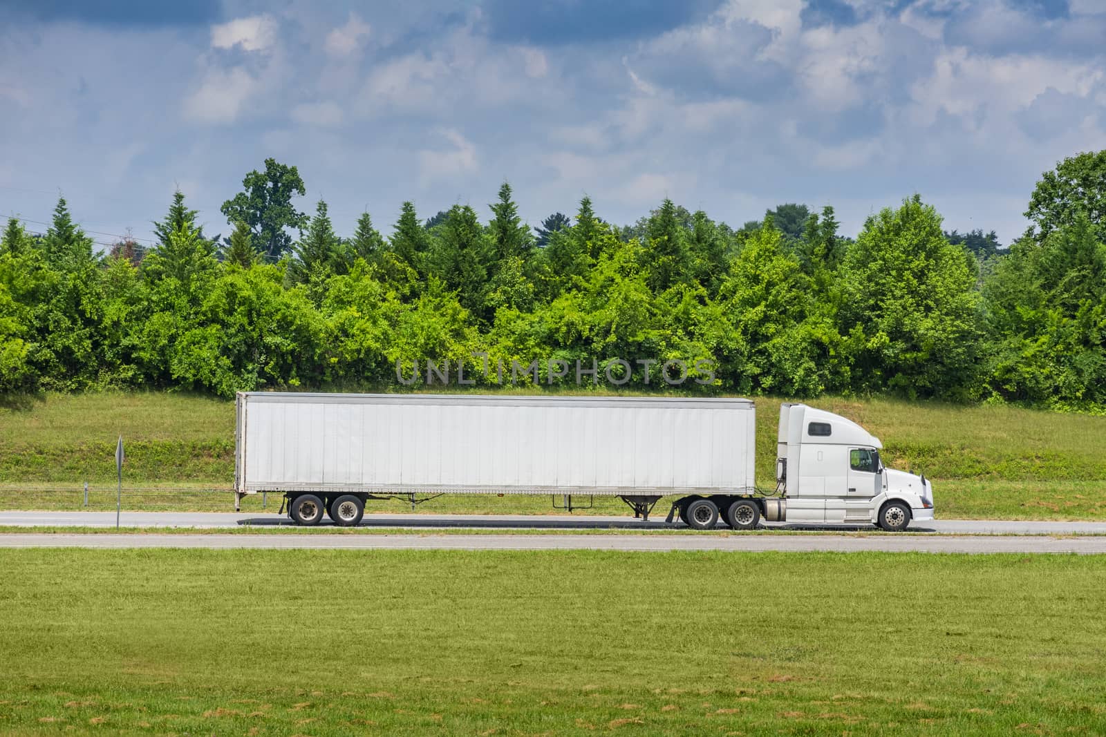 Horizontal side view shot of a white tractor-trailer with a blank trailer that would make great copy space.