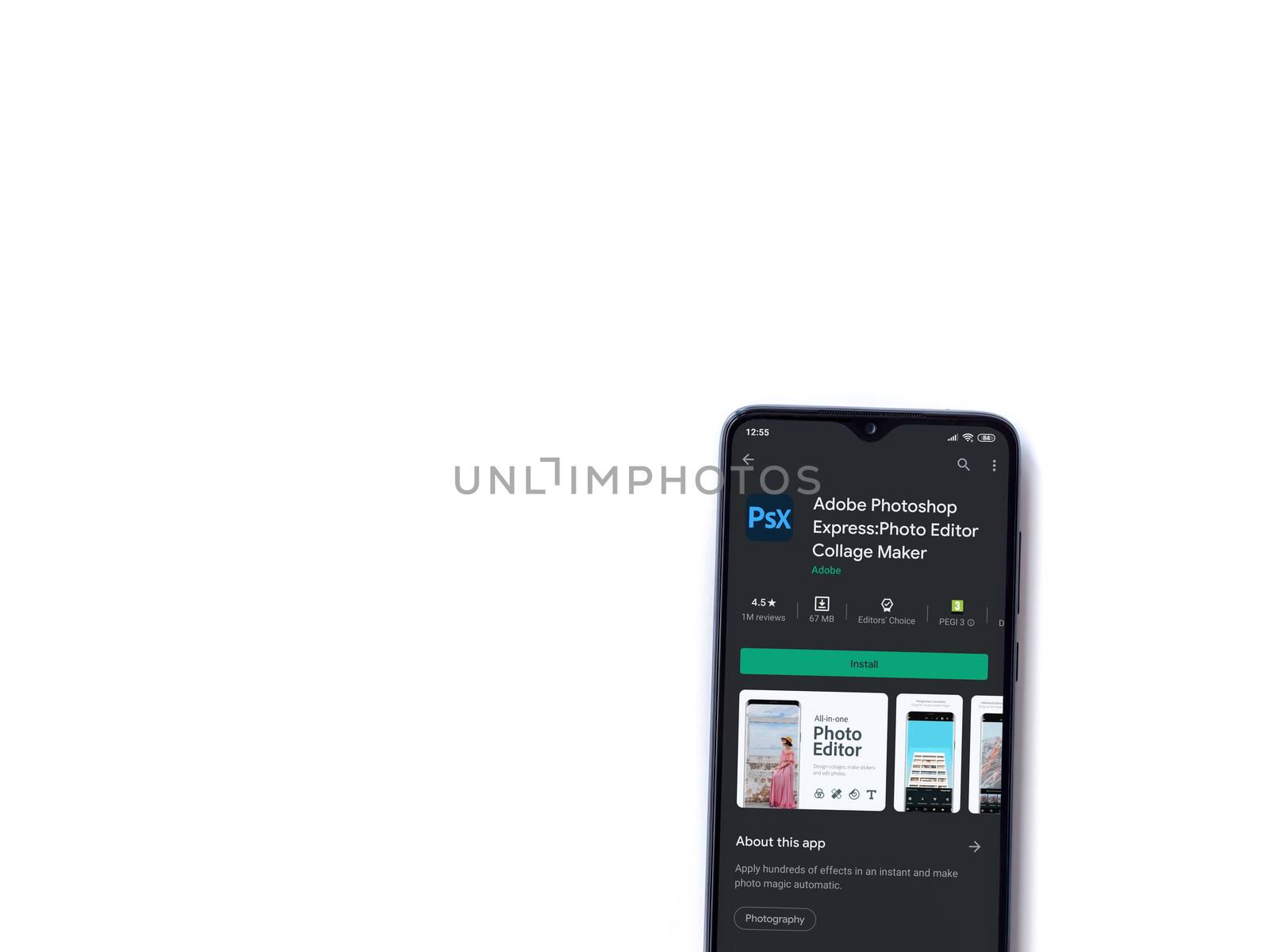 Lod, Israel - July 8, 2020: Adobe Photoshop Express Photo Editor app play store page on the display of a black mobile smartphone isolated on white background. Top view flat lay with copy space.