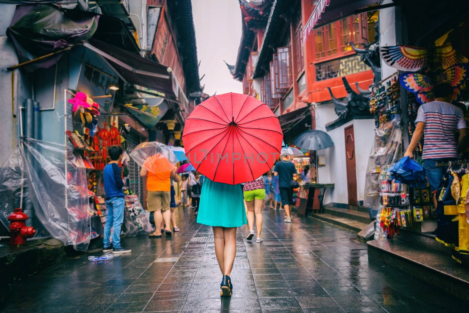 People woman walking in chinatown shopping street. Rainy day girl tourist under red oriental umbrella in narrow alleys on china travel in Shanghai by Maridav