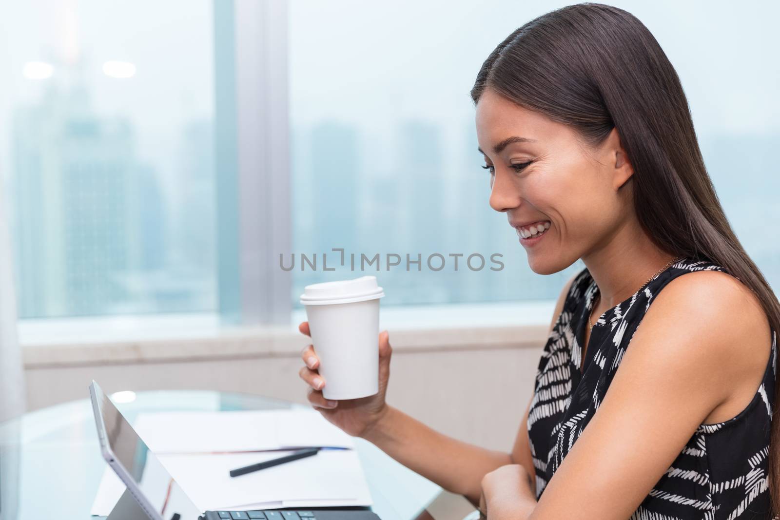 Businesswoman drinking coffee working on laptop by Maridav