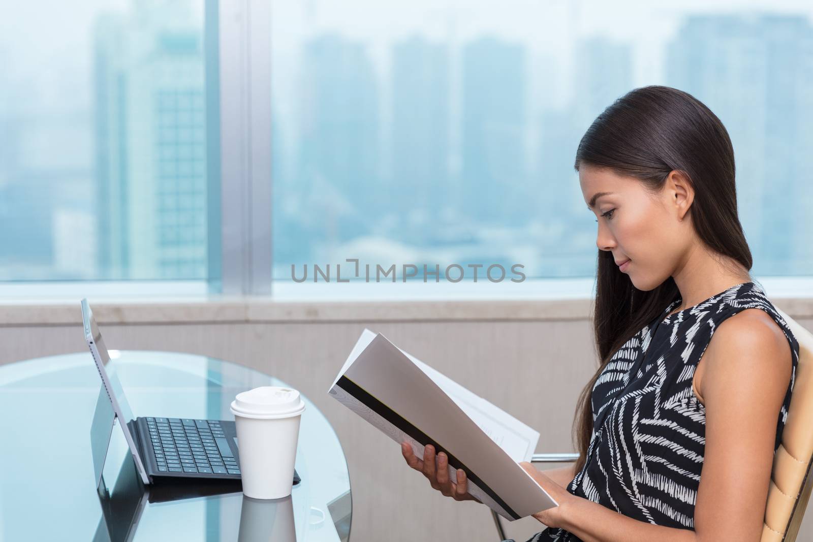 Asian chinese businesswoman reading documents studying paperwork at desk. Businesswoman, lawyer or accountant doing contract work in city office in Shanghai, China.