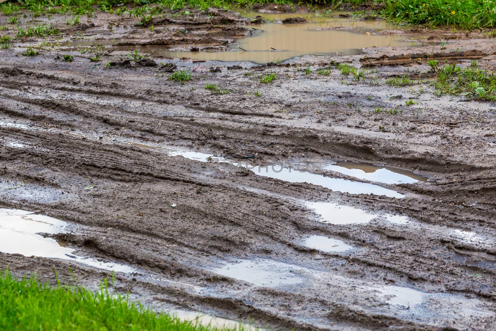 dirty clay mud road with puddles and tire tracks - closeup with selective focus and blur, diagonal composition