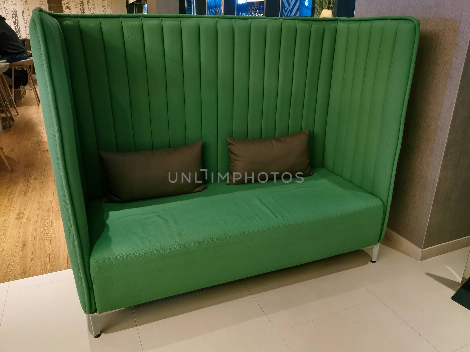 Green sofa with two small pillows in a hotel lobby by sonandonures