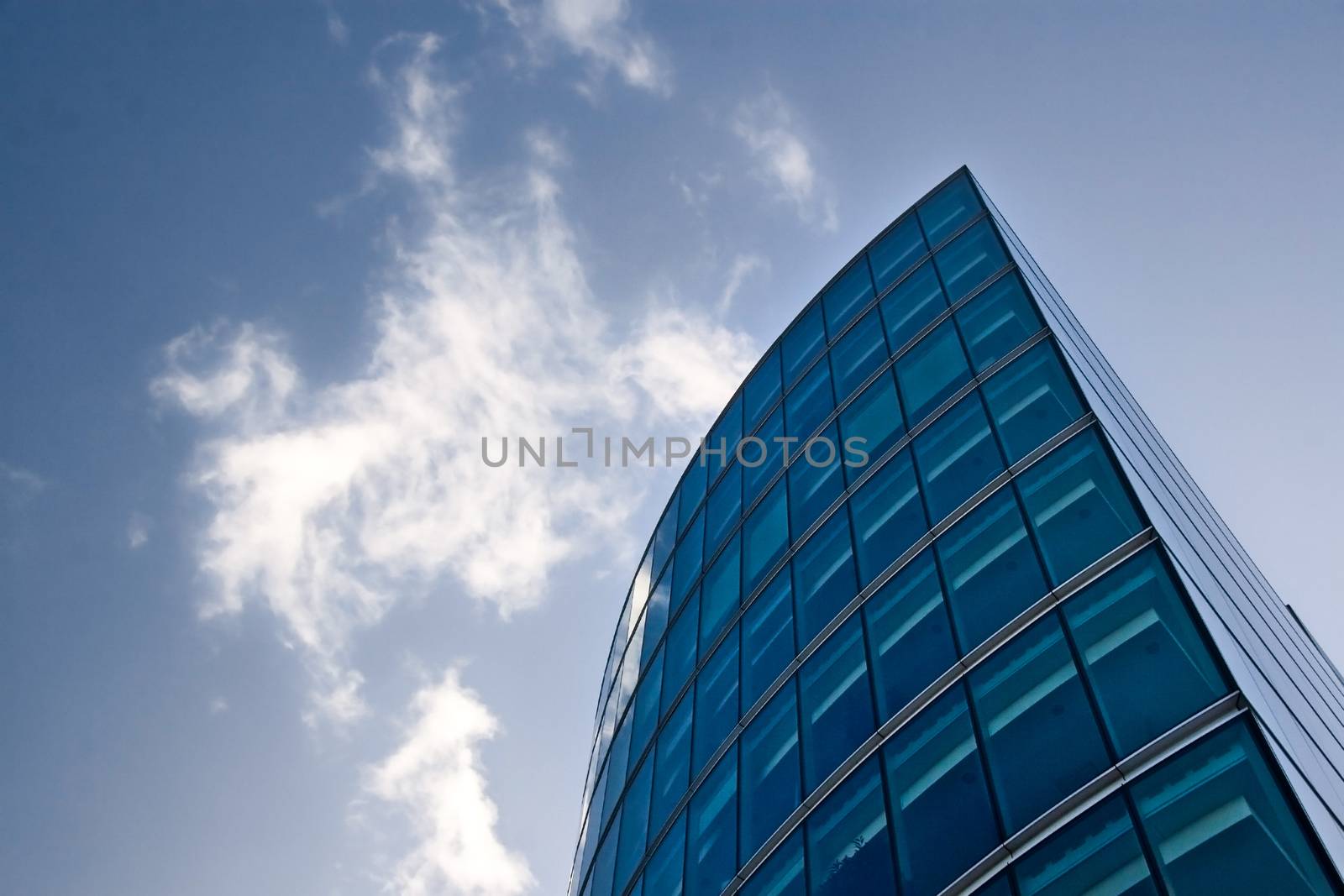 Part of modern glass and steel building forming lines against deep blue skies