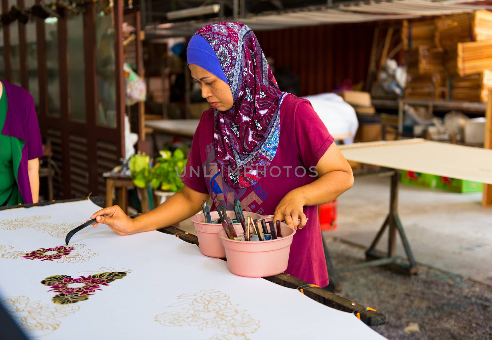 Penang, Malaysia -- March 8, 2016  Woman paints in a stencil in a Batik factory in Penang, Malaysia. Editorial Use Only