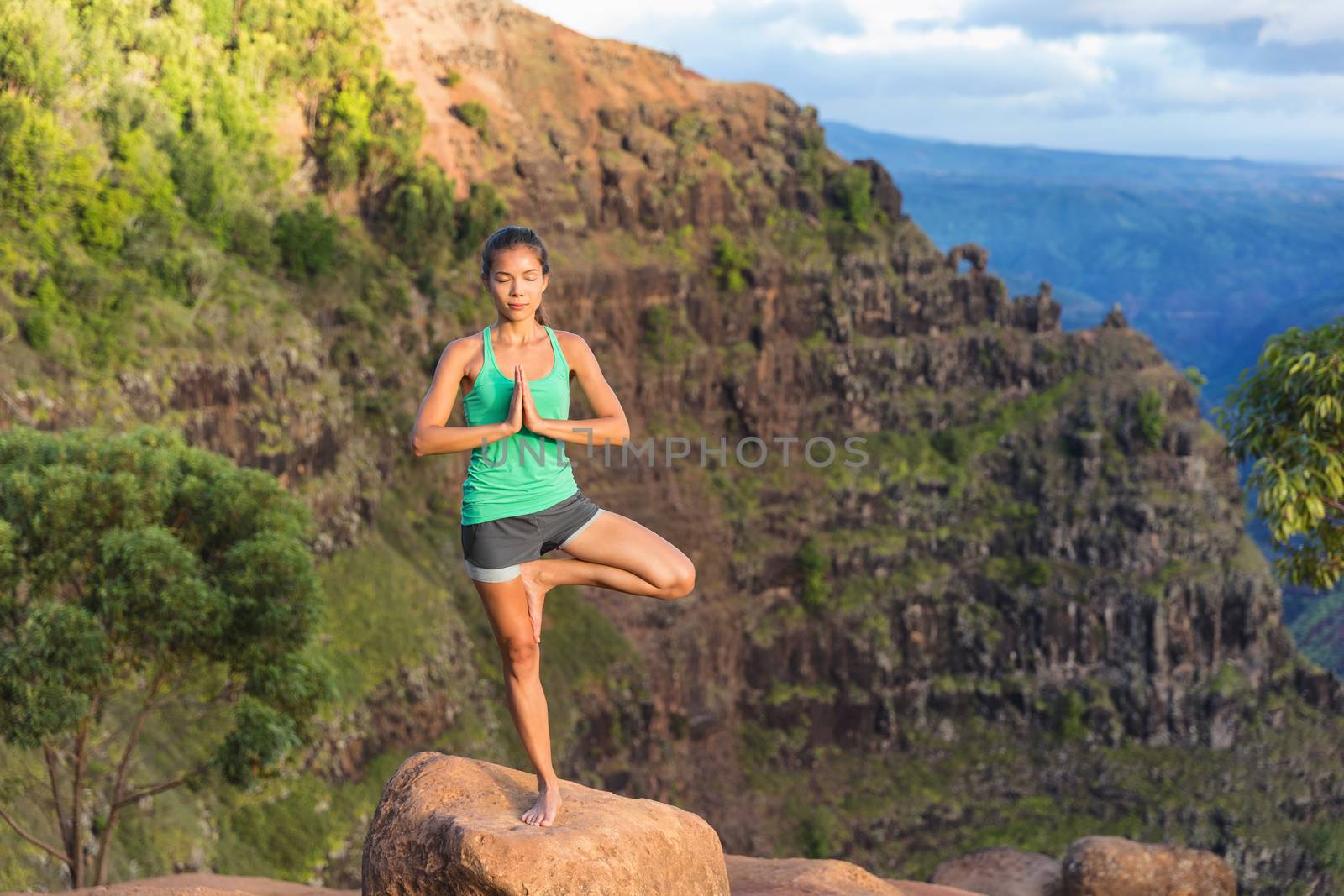 Yoga meditation - woman meditating doing yoga tree pose on Kauai, Hawaii, USA. Serene relaxing girl in amazing nature landscape in Waimea Canyon.