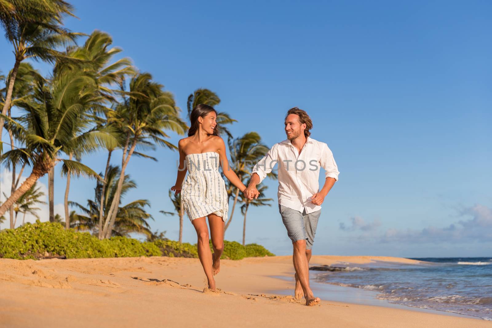 Happy couple running on the beach, romantic getaway. Waiohai, Poipu in Kauai, Hawaii by Maridav