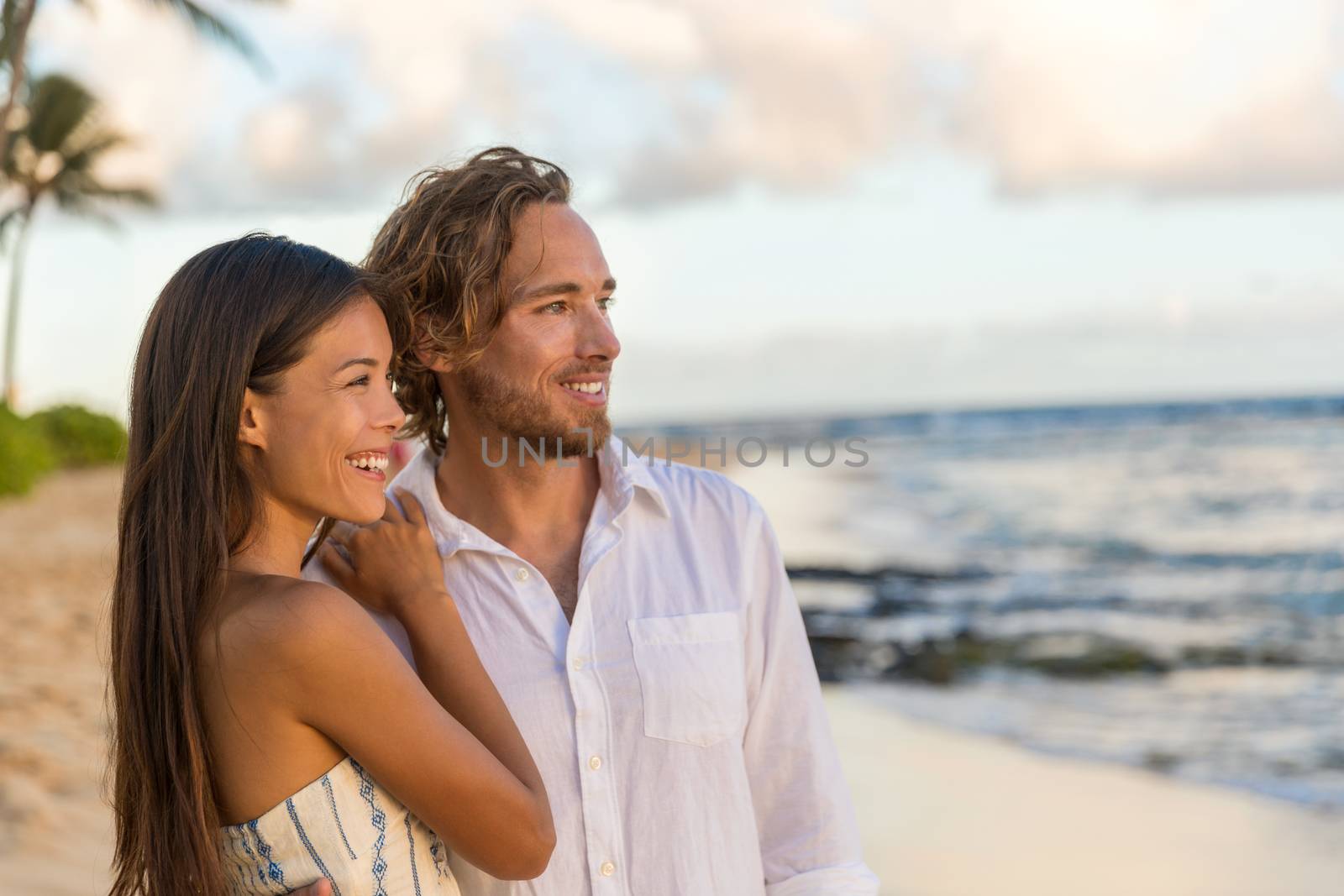 Couple enjoying honeymoon vacation tropical beach. Portrait of happy Asian girl and Caucasian man smiling relaxing on summer travel holidays. Luxury resort newlyweds concept by Maridav