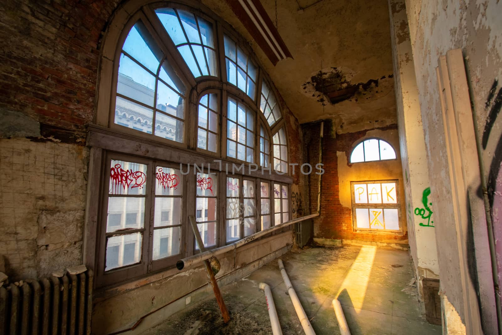 A Small Room in an Abandoned Building With a Large Arched Window by bju12290
