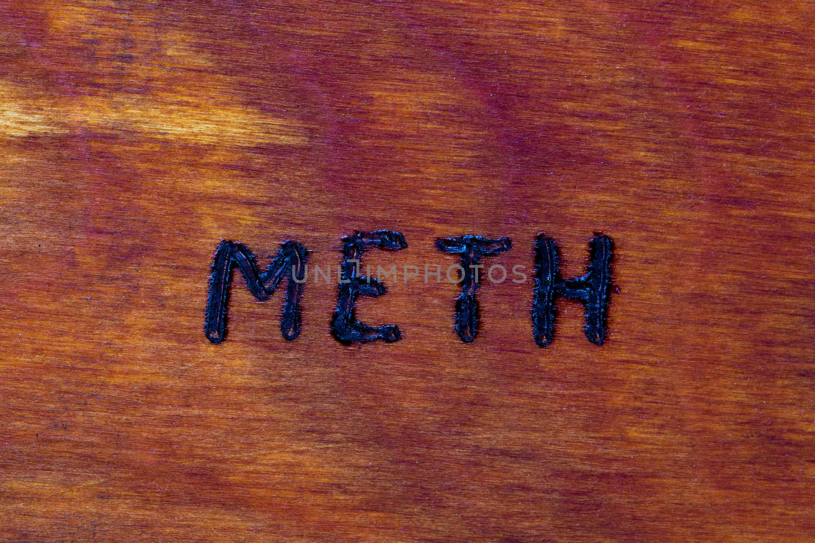 the word meth for Methamphetamine - burned by hand with woodburner on brown wood flat surface by z1b