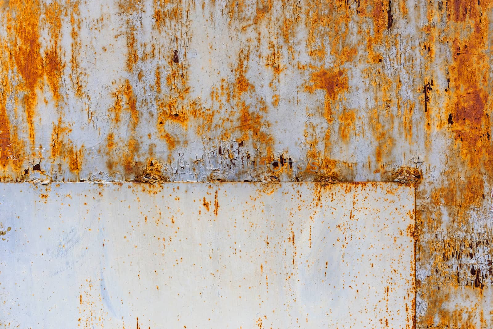 rusted flat sheet metal surface with leftovers of white and light blue paint, with rectangular patch in the corner.