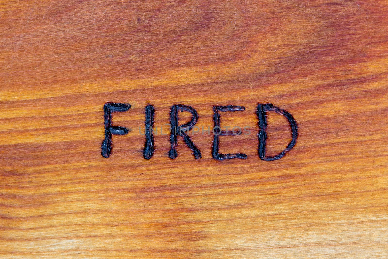 the word fired handwritten with hand woodburner on flat brown wood surface in flat lay directly above composition