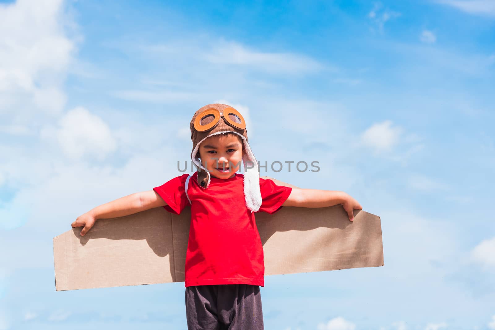 Kid little boy smile wear pilot hat play with toy airplane wing  by Sorapop