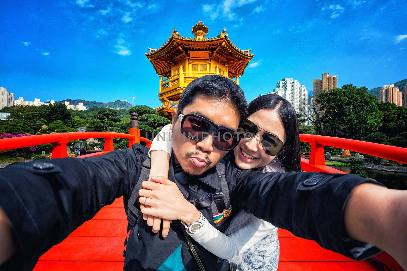 Young Couple in sunglasses Tourists in Gold Chinese pavilion Temple at the park in Hong Kong