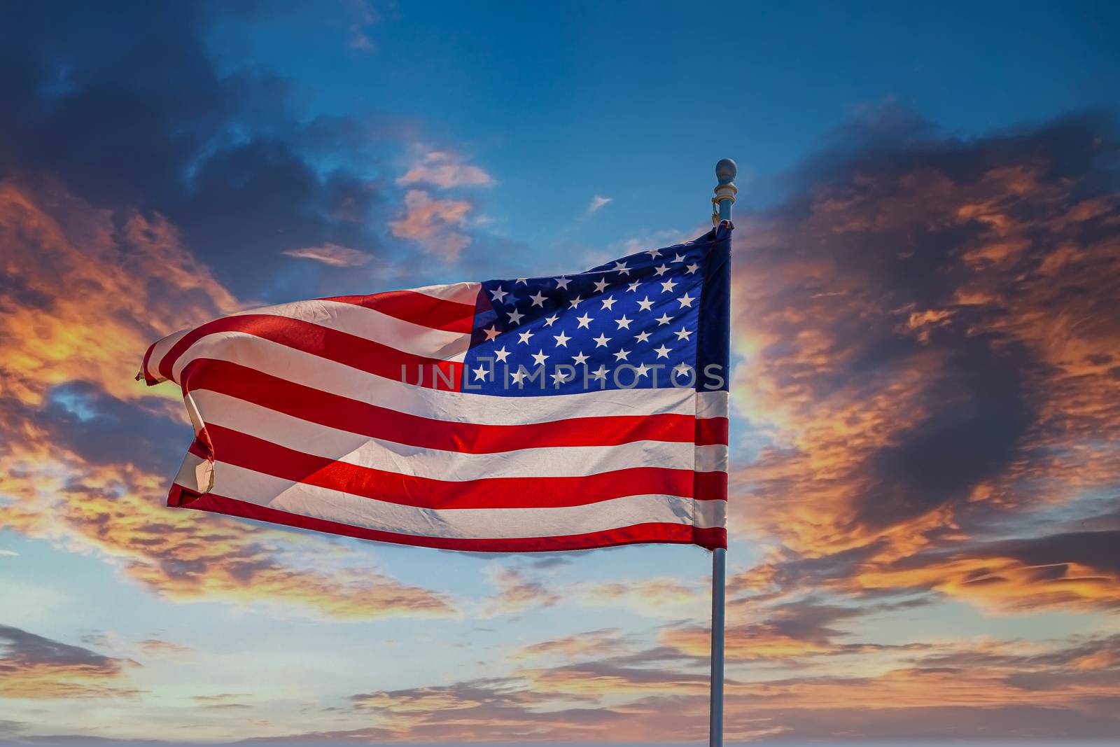 The American Flag Unfurling in Wind on Clear Blue Sky
