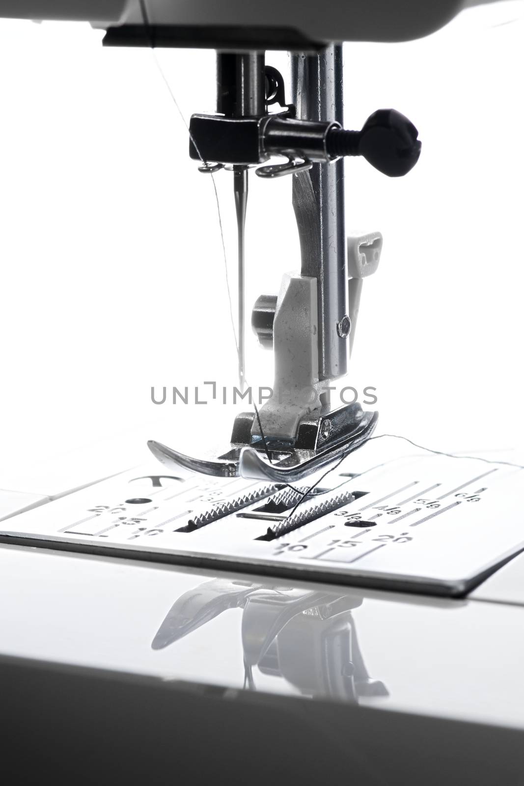 9 - Vertical close up macro image of bright needle and sewing machine working area.
