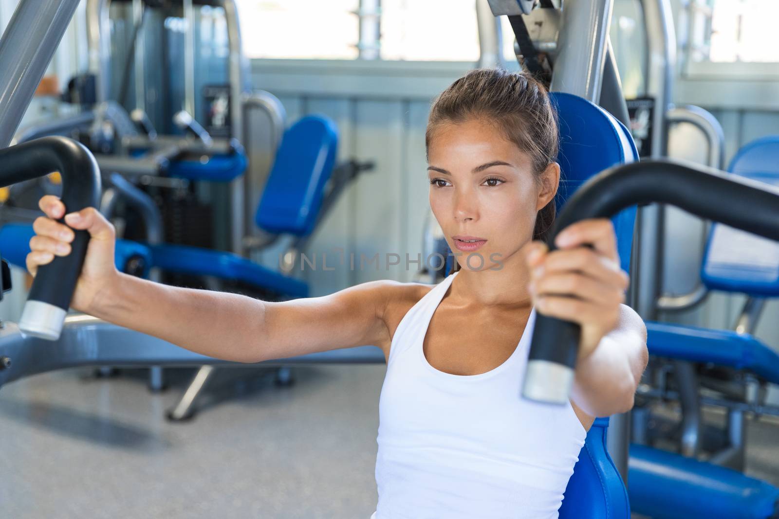 Gym workout Asian woman focused and motivated training on pec deck fly machine. Fitness workout.