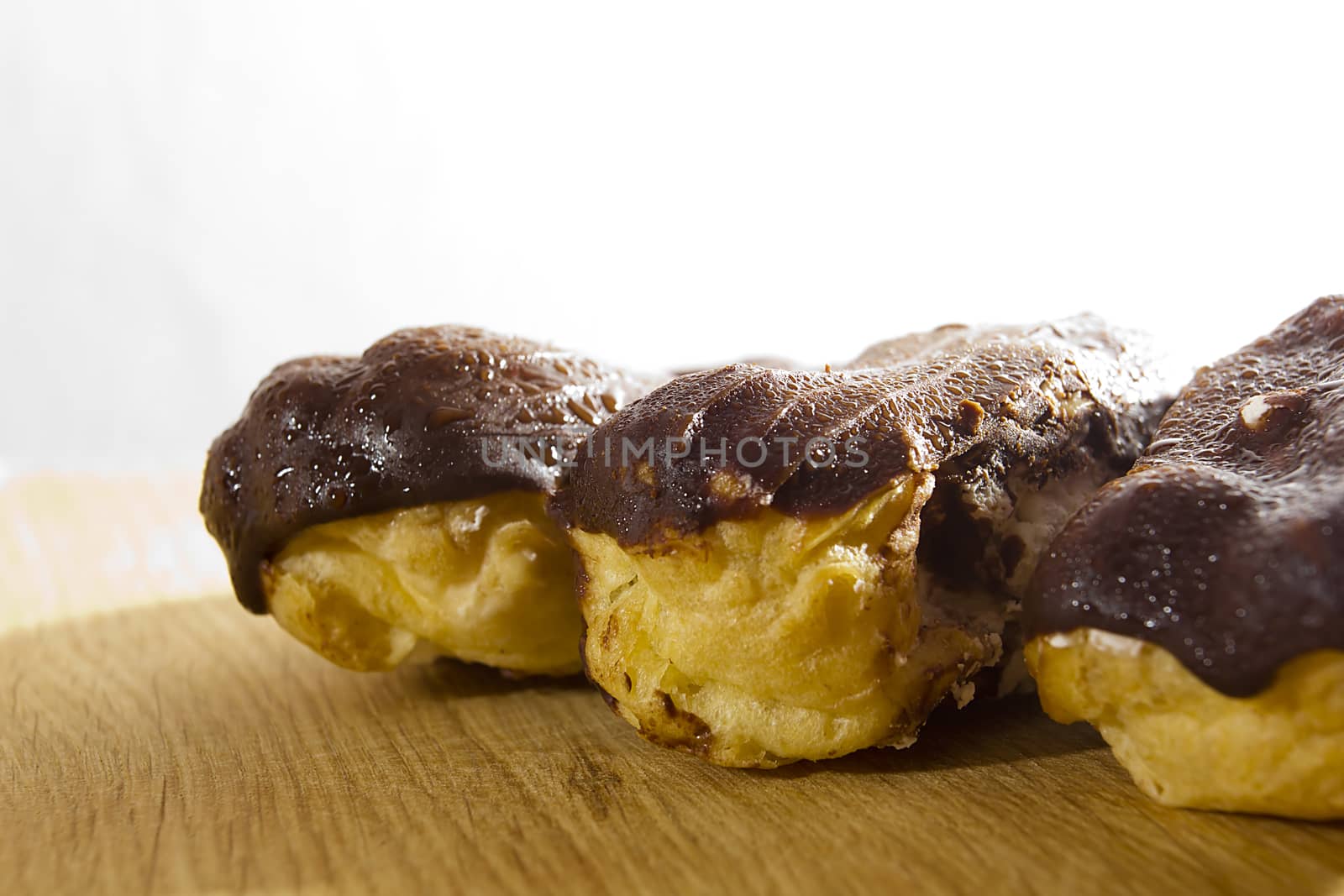 Eclairs with chocolate icing on a wooden table