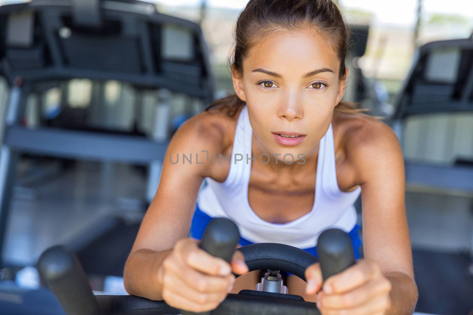 Endurance training fitness woman doing cardio workout. Exercise on gym bike bicycle by Maridav