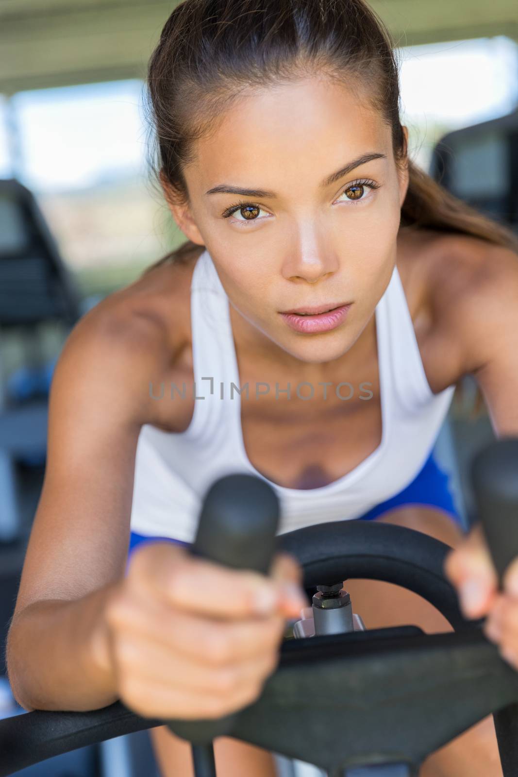 Asian woman training cardio workout at home on indoor bike. Working out to get in shape. Concept for weight loss. Motivated and focused young girl.