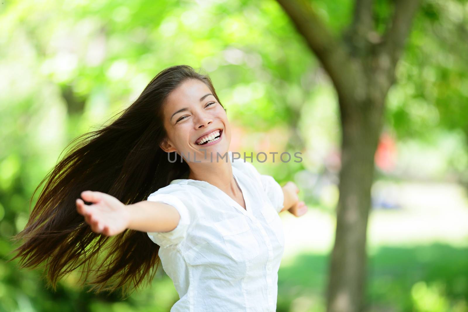 Cheerful young woman with arms outstretched enjoying in park. Portrait of beautiful female is in casuals. Joyful woman is enjoying nature during summer.