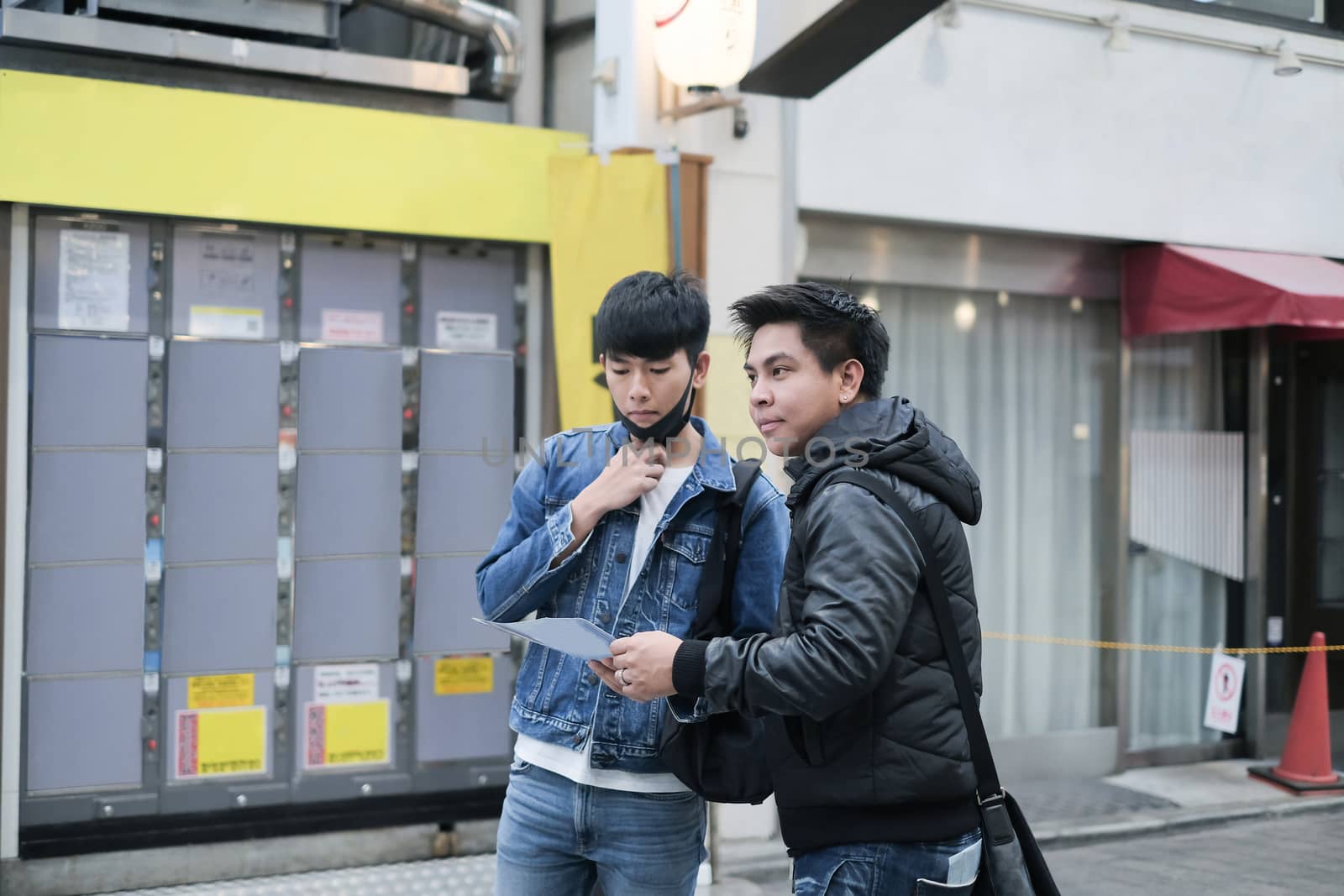 Two young handsome asian men travel in the city on walking street and searching the way to visit the best famous place