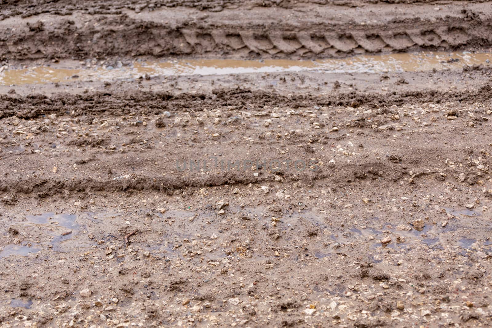 dirty clay mud road with puddles and tire tracks - closeup with selective focus and blur