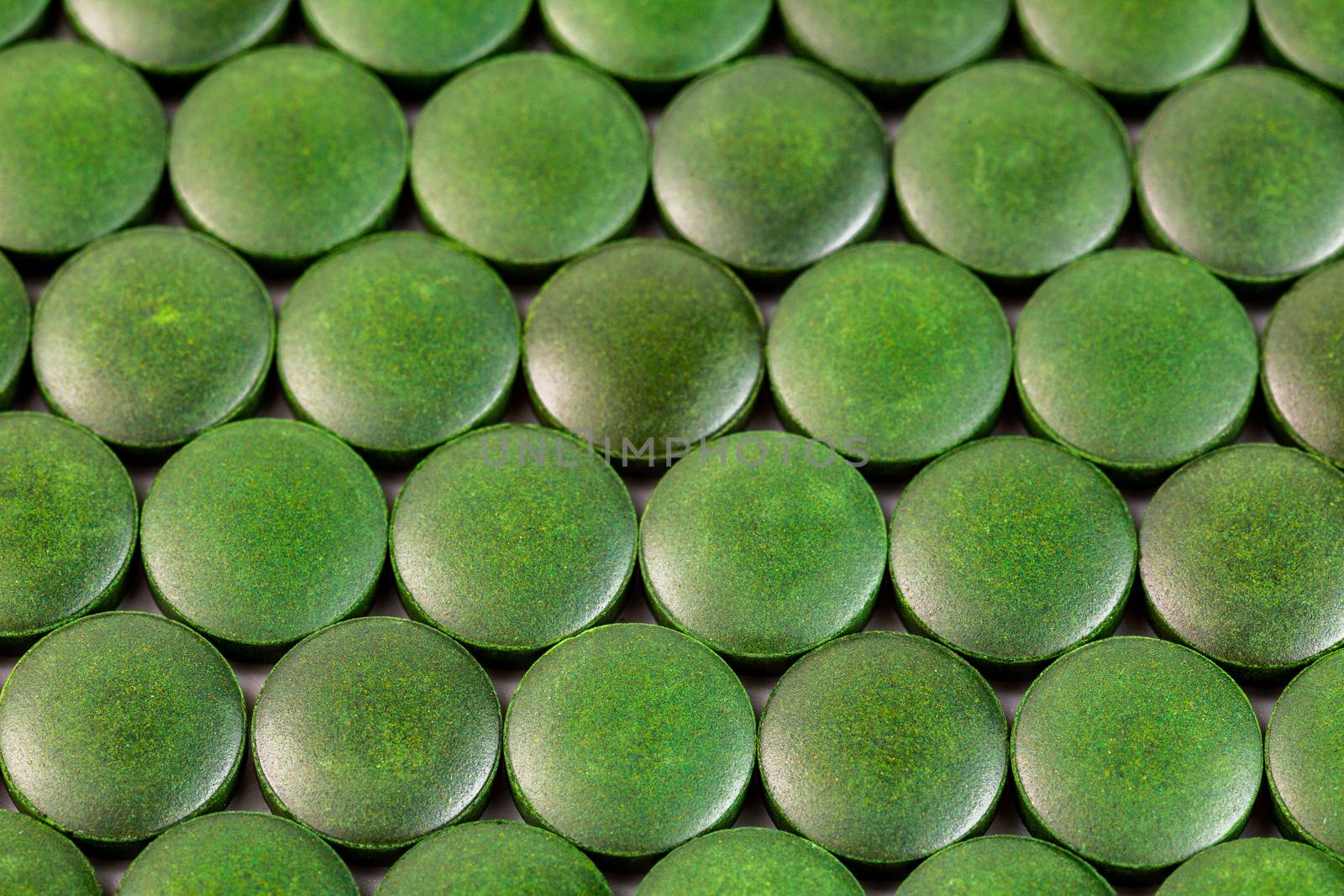 close-up background of many green organic spirulina tablets laid tight in one layer on flat surface by z1b