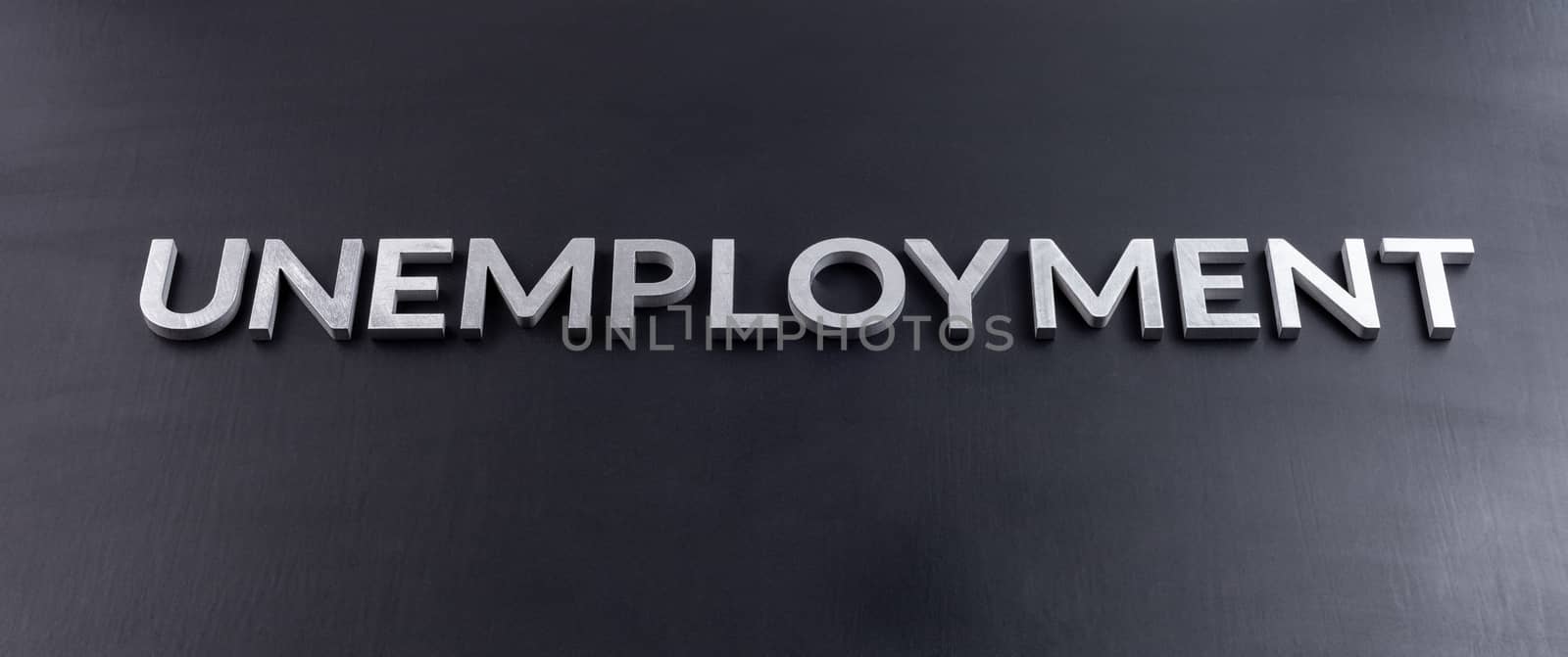 the word unemployment laid with aluminium letters on matte black flat surface with slanted perspective