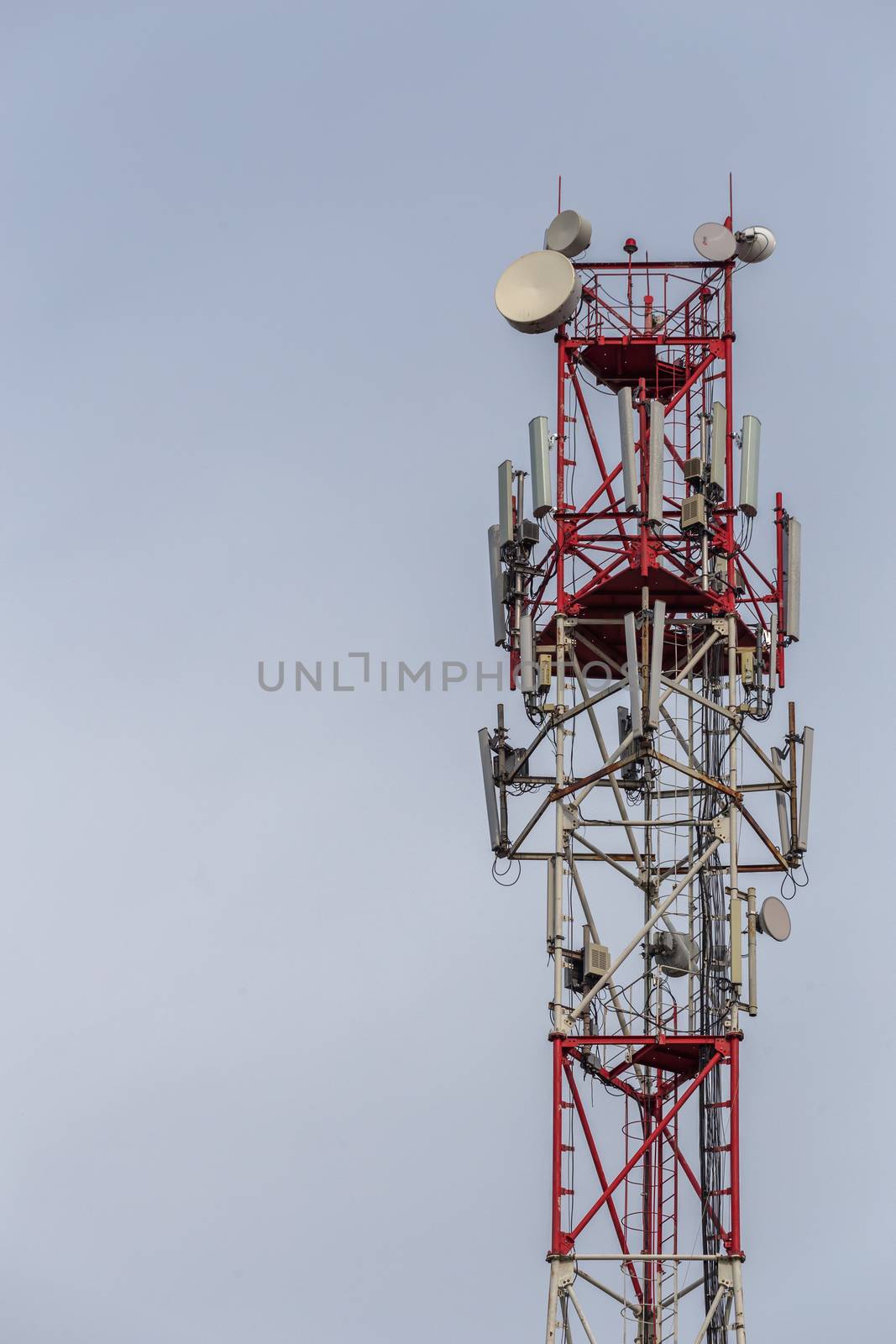 3G, 4G, 5G, wireless and cell phone telecommunication tower close-up on cloudy daylight sky background, vertical shot