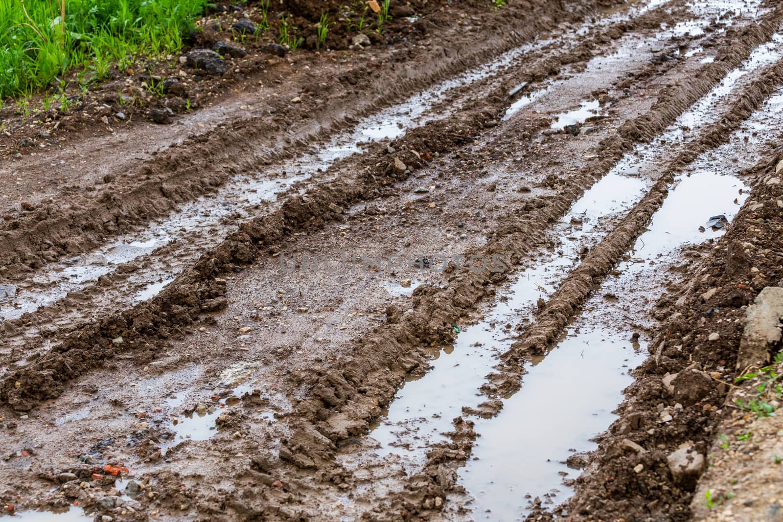 dirty clay mud road with puddles and tire tracks - closeup with selective focus and blur, diagonal composition