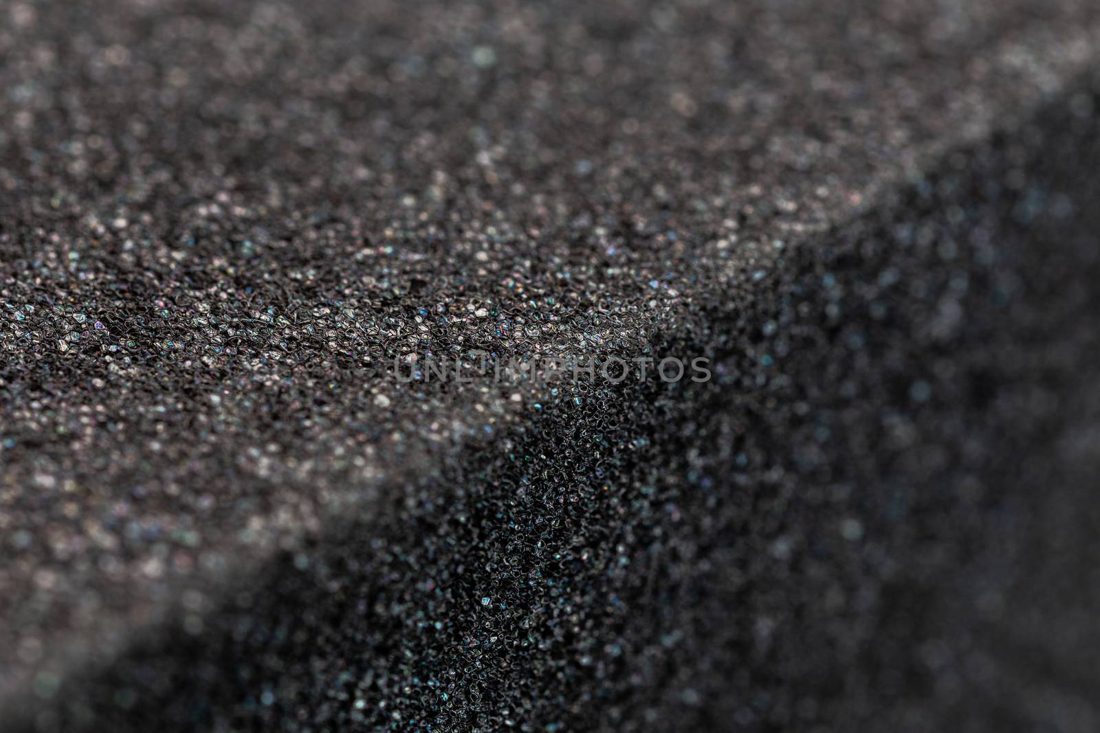 Close-up view of an edge of black rubber foam sponge brick. Selective focus with shallow depth of field.