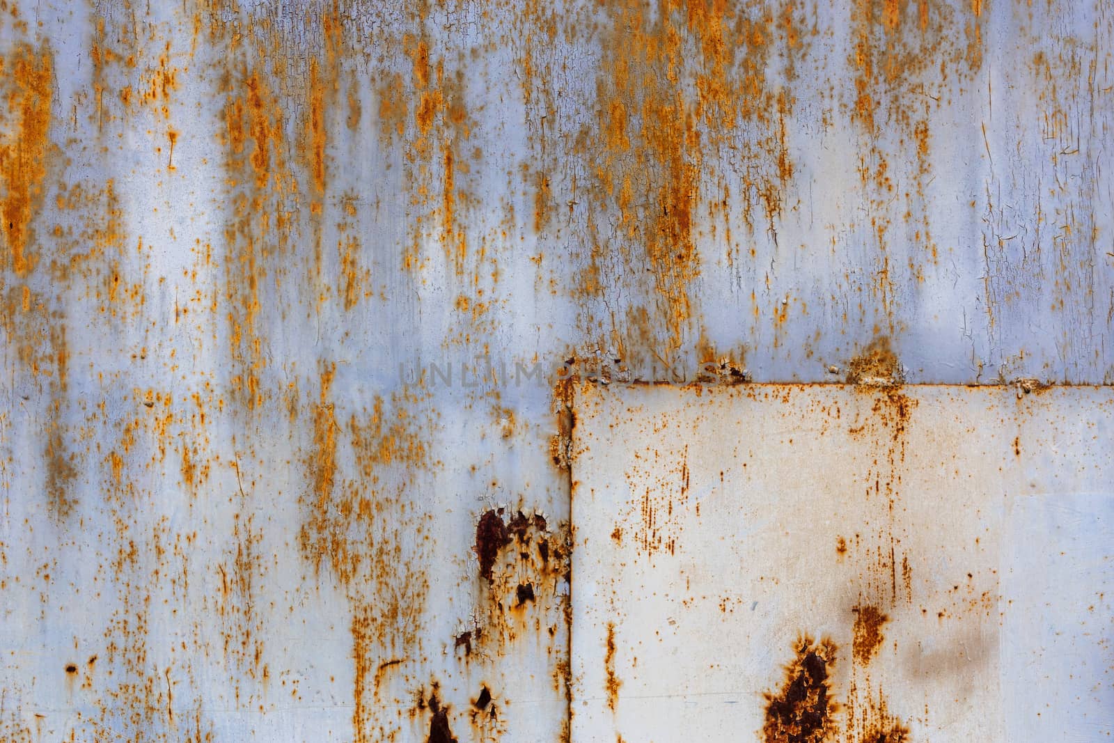 rusted flat solid sheet metal surface with leftovers of white and light blue paint, with rectangular patch in the corner.