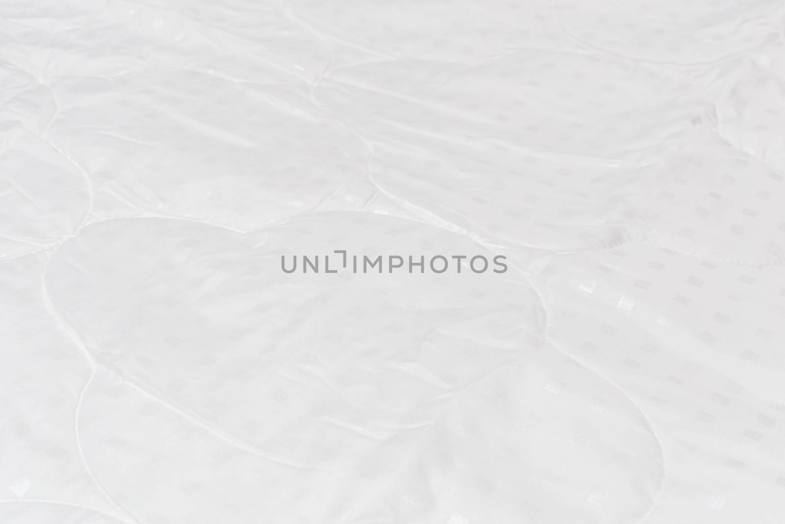 White fabric blanket close-up backdrop with selective focus and background blur. Small white squares pattern.