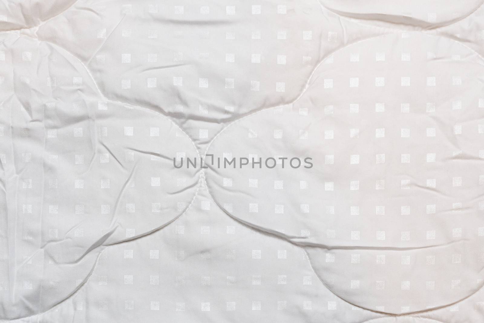 White fabric blanket close-up texture and background. Small white squares pattern.