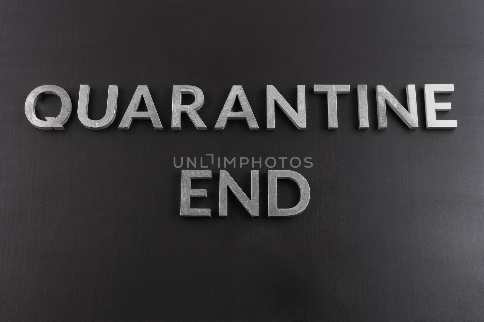the words quarantine end laid with silver metal letters on matte back flat surface directly above in flat lay perspective, end of restrictions concept