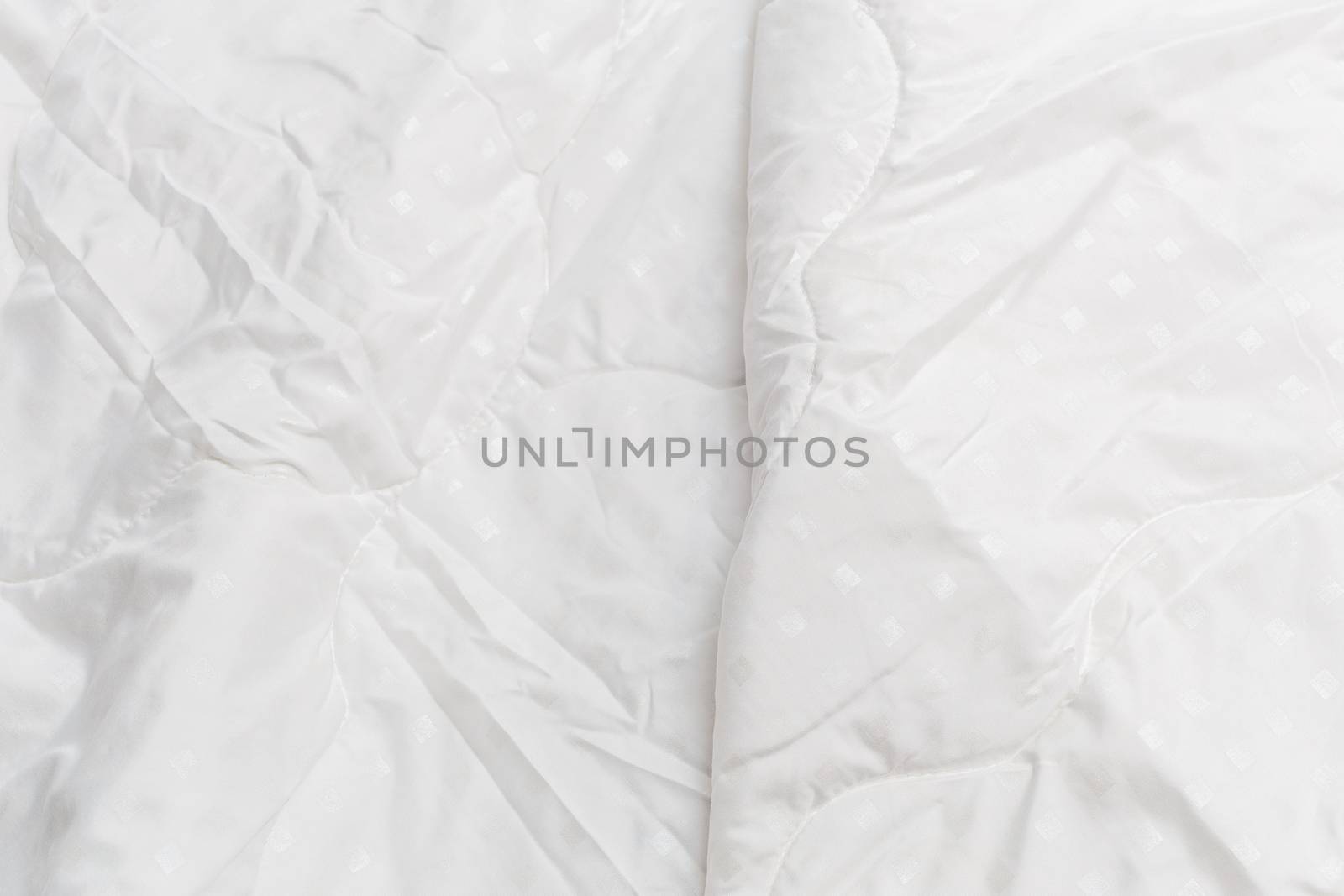White fabric blanket close-up backdrop with selective focus and background blur. Small white squares pattern.