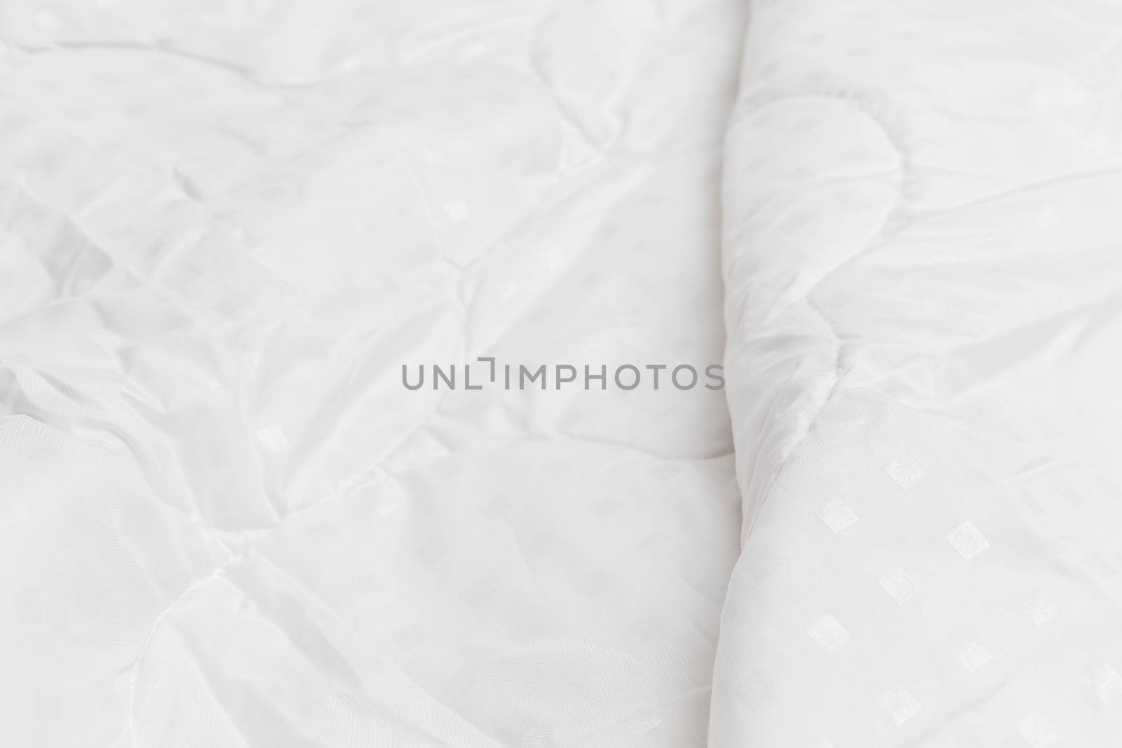 White fabric blanket close-up backdrop with selective focus and background blur. Small white squares pattern.